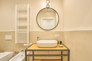 A bathroom with a white sink, a round mirror, and a towel rack. - La Marina (Naples)