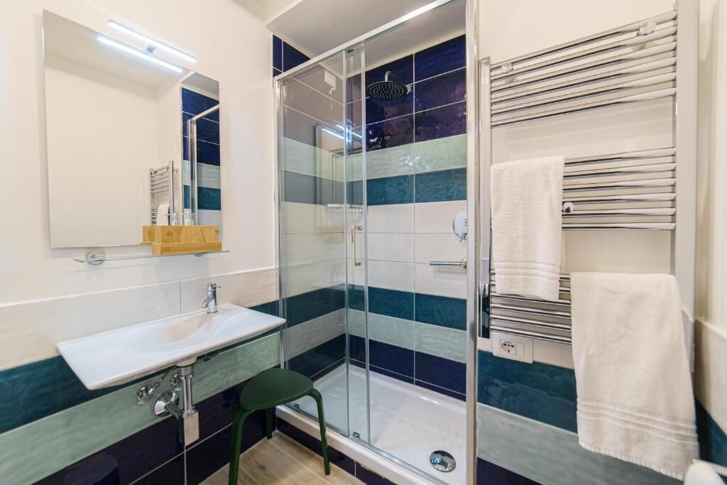 A modern bathroom with a glass shower enclosure, a sink, and a towel rack.