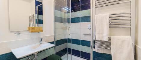 A modern bathroom with a glass shower enclosure, a sink, and a towel rack.