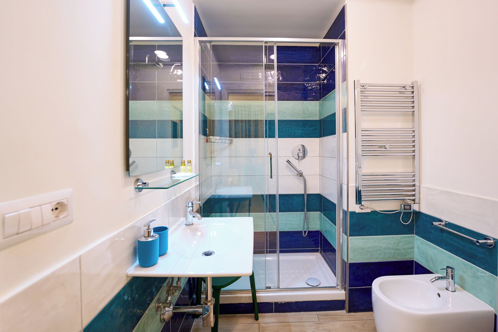 A modern bathroom with a glass-enclosed shower, a white sink, and a bidet.