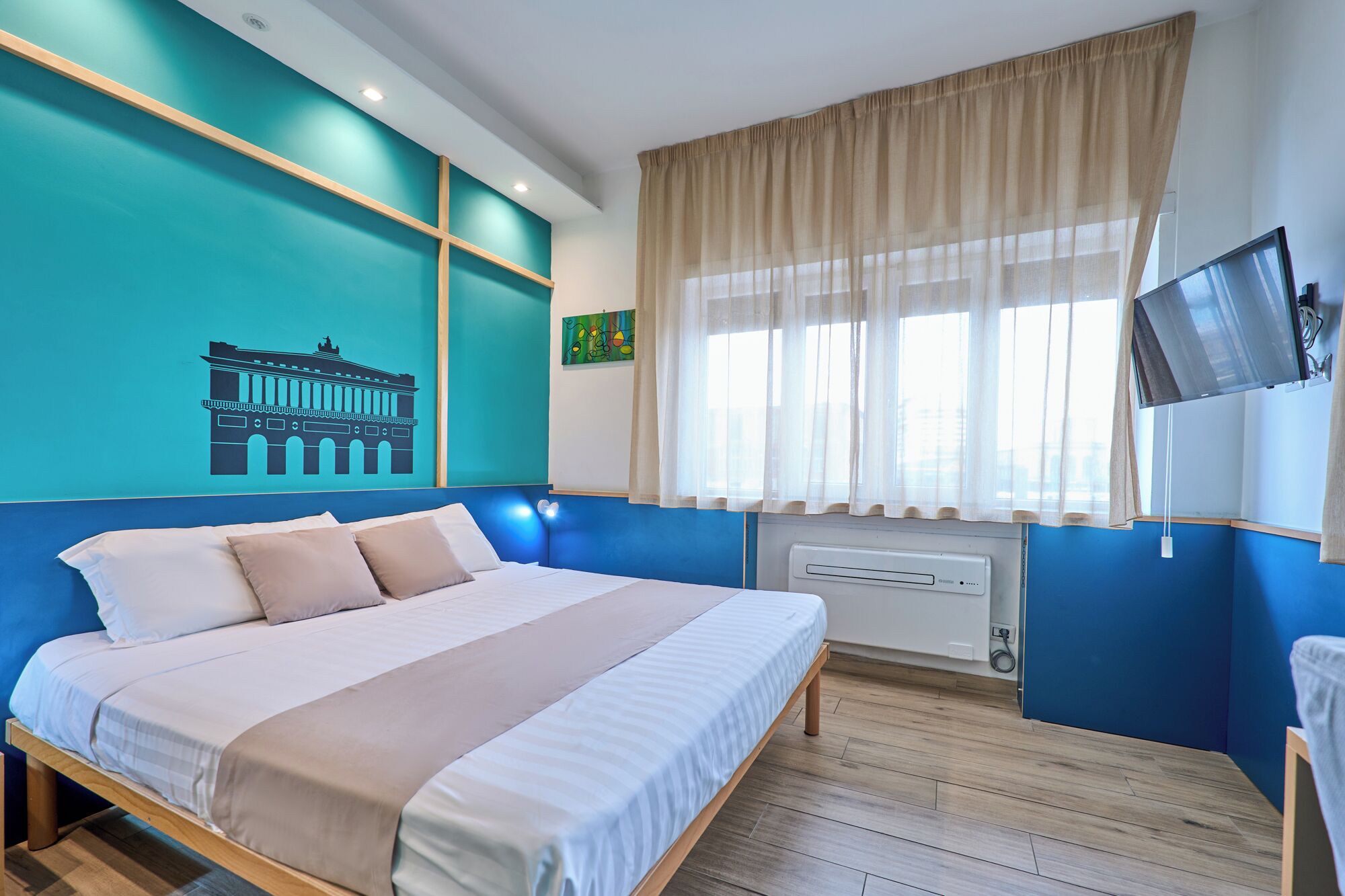 A bedroom with a bed, a TV, a window with curtains, and a radiator.