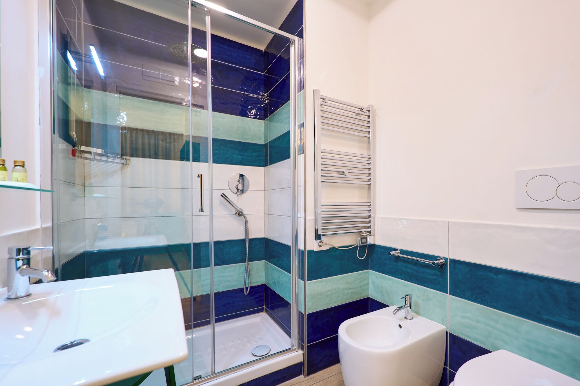 Un baño moderno con cabina de ducha de vidrio, lavamanos blanco y retrete.
