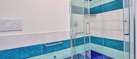 A bathroom with a glass-enclosed shower, a white sink, and a towel rack.