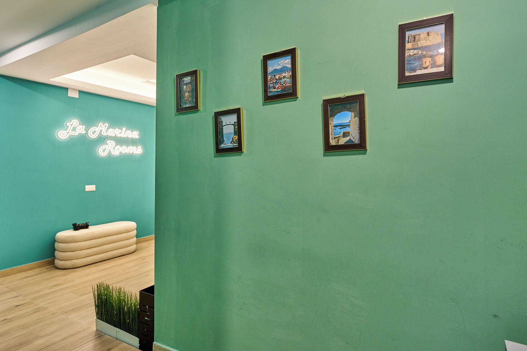 A teal-walled room with a neon sign reading "Le Marina Rom."