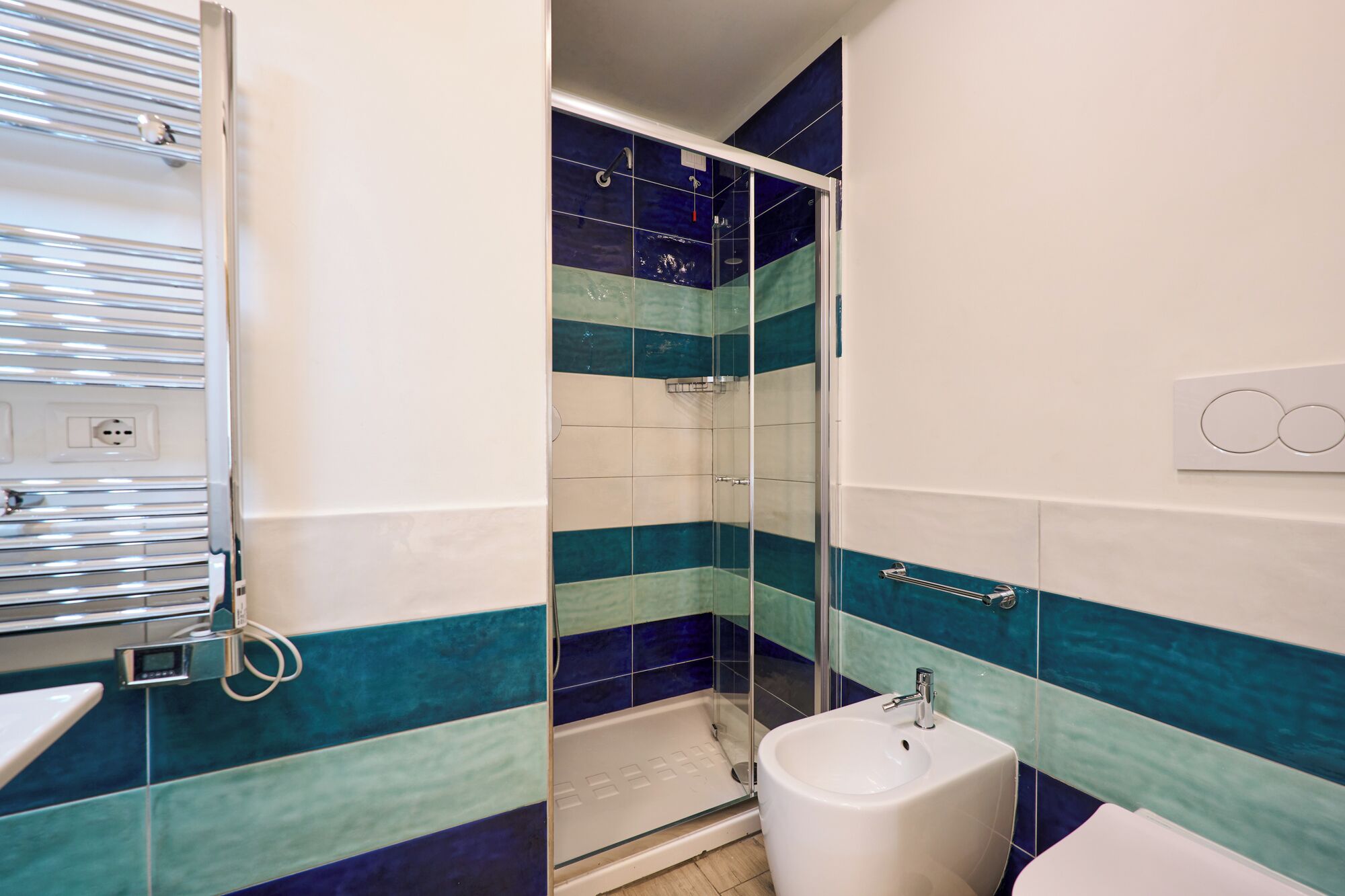 Een badkamer met een douche, een toiletbril en een handdoekhouder.