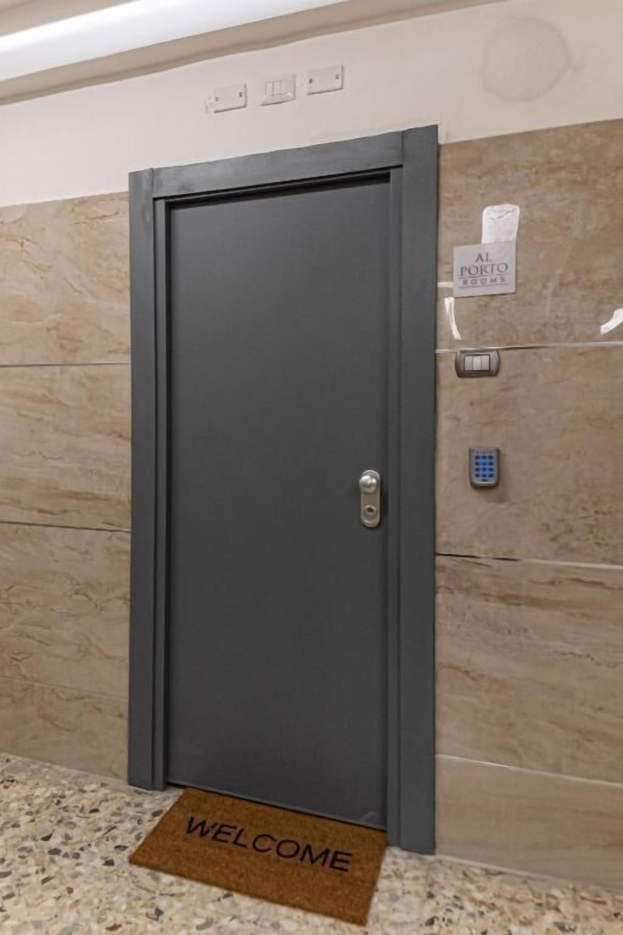 A modern elevator door with a keypad and a sign indicating "Al. Ponto Rooms".