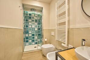 A bathroom with a glass shower enclosure, a toilet, and a sink with a mirror. - La Marina (Naples)