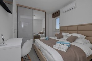 A modern hotel room with a bed, bedside table, and a desk with a chair.