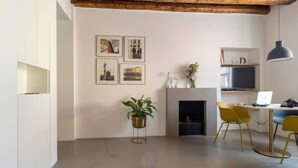 Un salon moderne avec une cheminée, un coin repas avec des chaises jaunes et une bibliothèque.