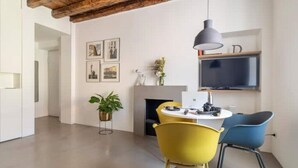 Une cuisine moderne avec un coin repas, comprenant une table ronde, deux chaises, un luminaire suspendu et un téléviseur à écran plat placé au-dessus du comptoir.