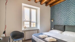 Une chambre à coucher avec un lit, une chaise, une fenêtre et un radiateur.