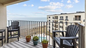 Un balcon avec deux fauteuils Adirondack, une petite piscine et une vue sur la plage et l’océan.