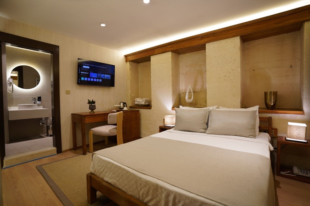 A hotel room with a bed, a desk, a chair, a television, and a bathroom.