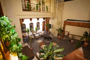 Un atrium à plusieurs niveaux, doté d’espaces aménagés avec des sièges, de plantes en pot et d’un foyer central.