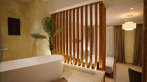 Une salle de bain moderne avec une baignoire, une douche, une plante en pot, un lit et un coin repas avec une chaise.