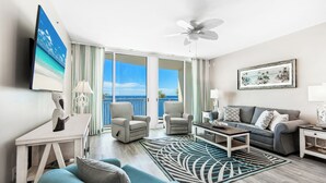 Ein geräumiges Wohnzimmer mit Balkon, Deckenventilator und Meerblick.