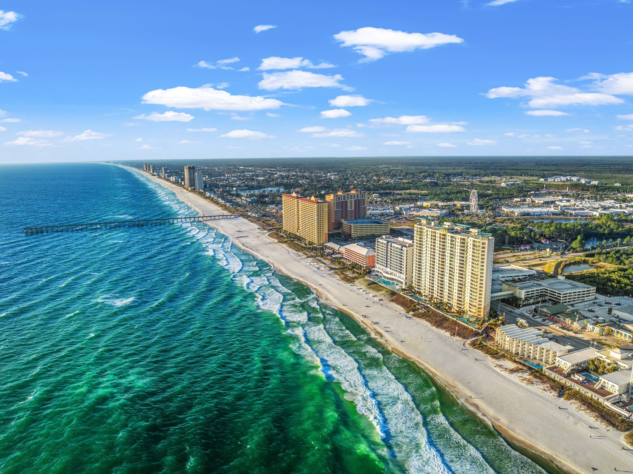 Un paisaje urbano costero con una playa, edificios altos y un cielo azul despejado.