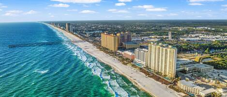 Un paisaje urbano costero con una playa, edificios altos y un cielo azul despejado.