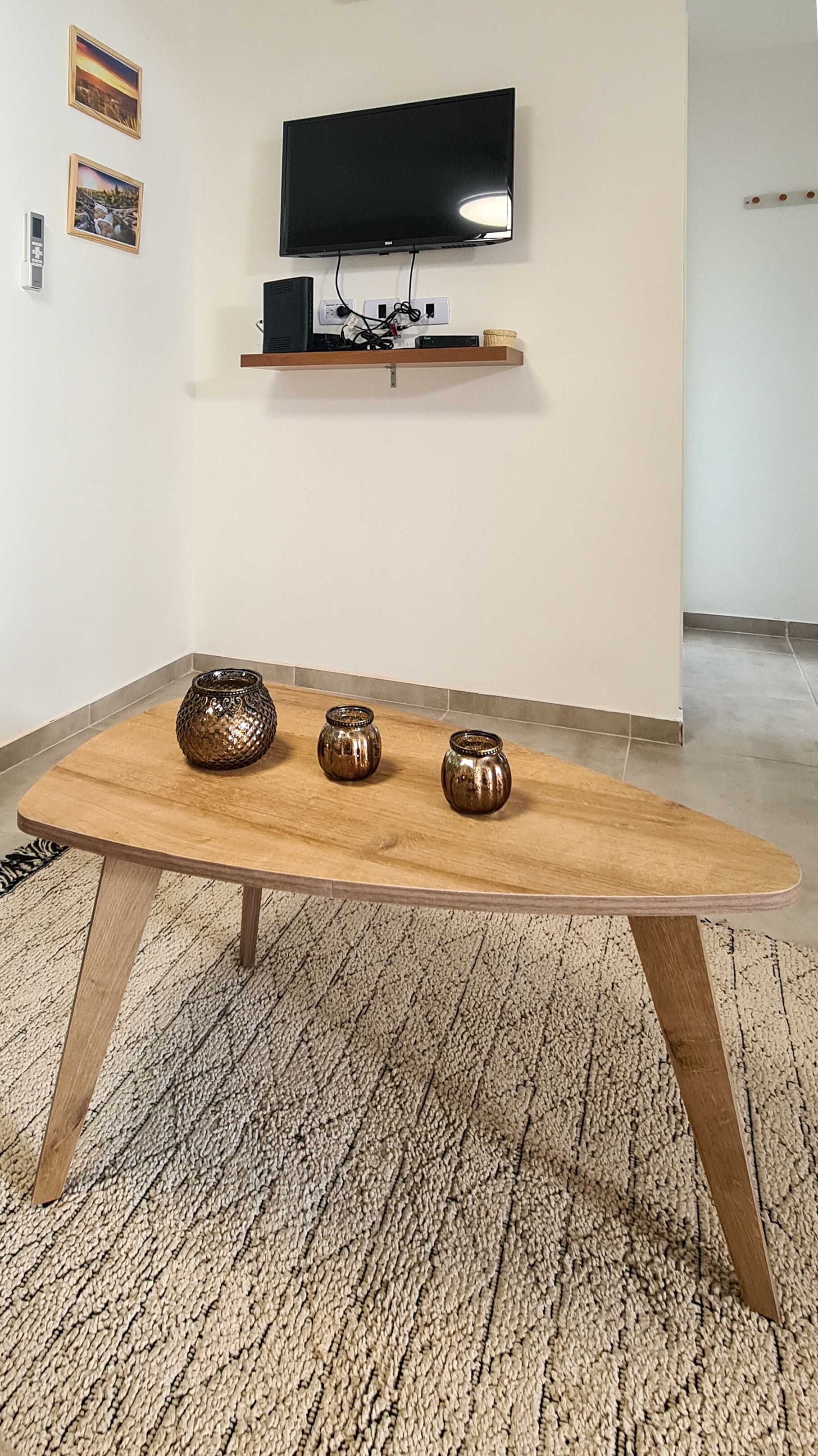 Een houten bijzettafeltje met drie decoratieve vazen op een kamerbreed tapijt.