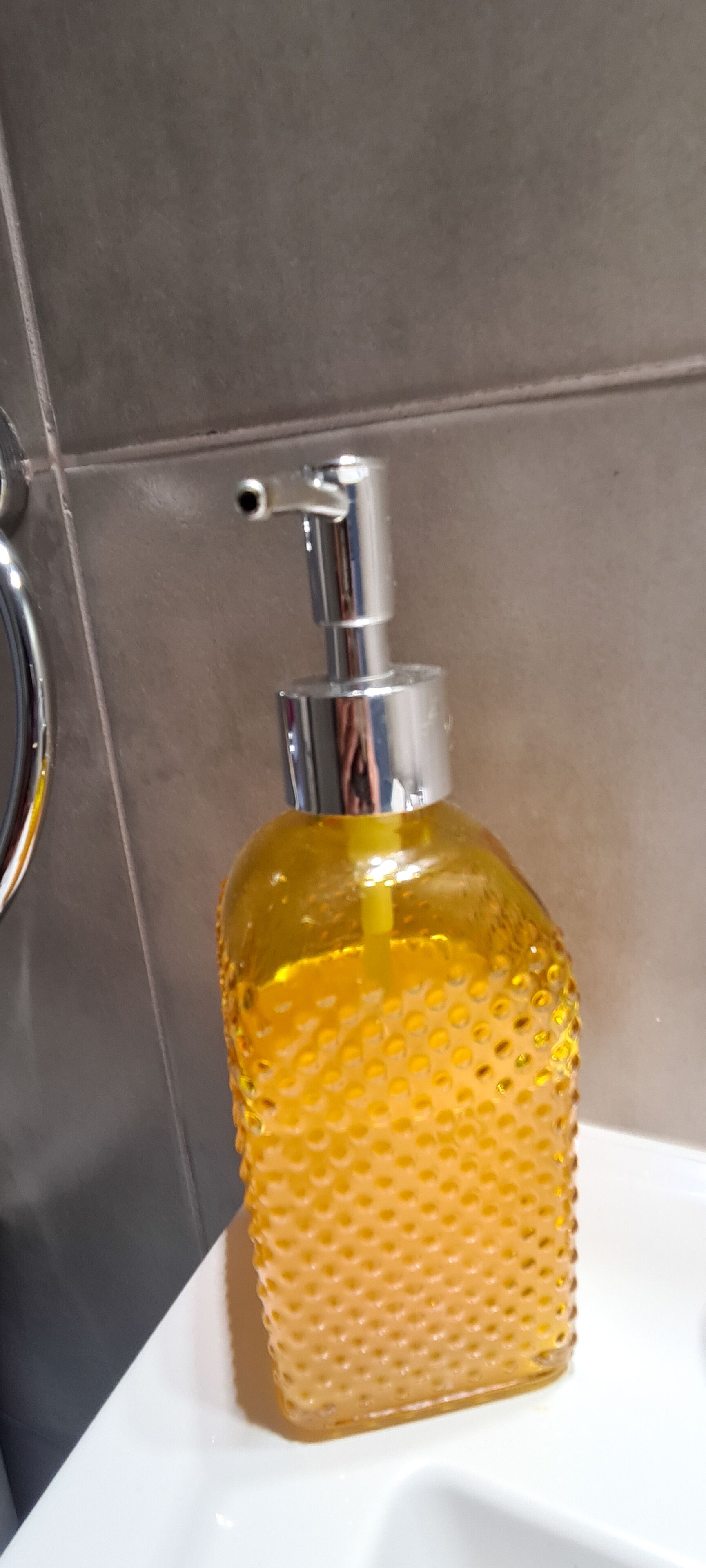 A bathroom with a yellow soap dispenser on a white sink.