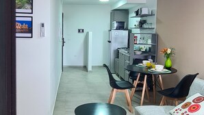 A modern living room with a sofa, two black tables, and a small dining area with chairs. - Lux Apart Cba (Córdoba)