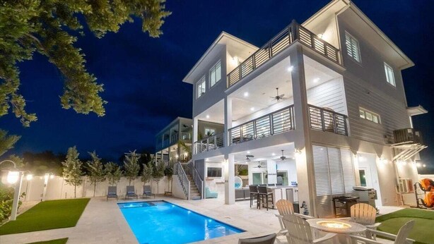 A two-story house with a swimming pool, outdoor seating, and a balcony.