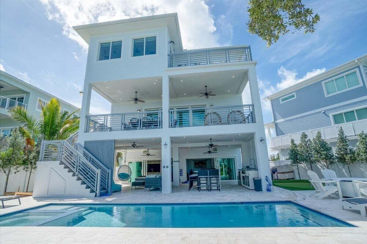 A two-story modern house with a swimming pool, outdoor seating, and a covered patio area.