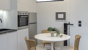 Une cuisine moderne dotée d’appareils électroménagers intégrés, une table de salle à manger ronde avec quatre chaises et un luminaire suspendu.