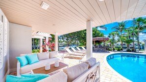 Un espace piscine abrité comprenant des chaises longues, un canapé et une petite table.