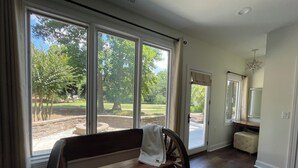 Ein Zimmer mit einer hölzernen Sitzbank, großen Fenstern und Blick auf einen Park.