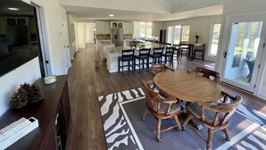 Eine geräumige Küche mit einer großen Kücheninsel, modernen Geräten und einem Essbereich mit Holzkästen und einem runden Tisch.
