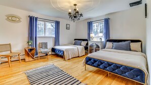 Een slaapkamer met twee bedden, een kroonluchter en een groot raam met gordijnen.