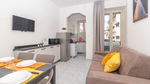 A compact living space with a kitchenette, dining area, and a sofa with cushions. - Casa Delia by Wonderful Italy (Torino)