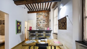 A cozy dining area with a wooden table, black chairs, and a brick wall. - Alle Mura del Molo Apartment by Wonderful Italy (Genova)