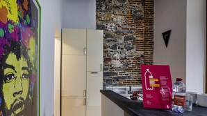A kitchen with a stone wall, a white cabinet, a red sign, and a water bottle on the counter. - Alle Mura del Molo Apartment by Wonderful Italy (Genova)