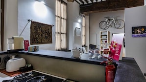 A kitchen with a gas stove, a toaster, a coffee machine, and a red fire extinguisher. - Alle Mura del Molo Apartment by Wonderful Italy (Genova)