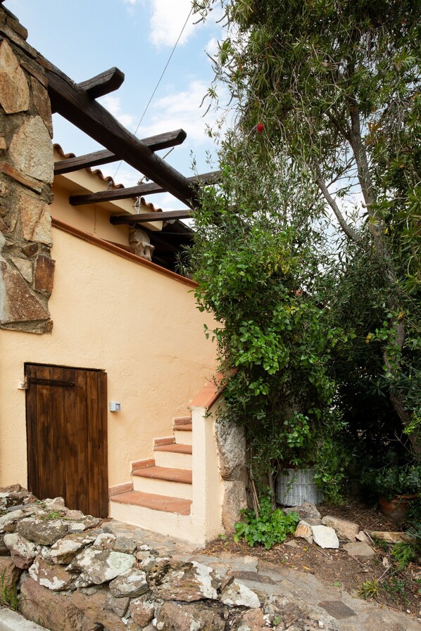 Un bâtiment en pierre doté d’une porte en bois et d’un escalier menant à une zone abritée.