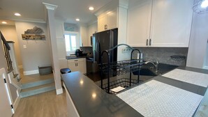 Una cocina moderna con armarios blancos, un refrigerador negro y una encimera negra.