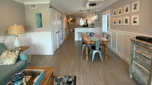 Una cocina amplia con una isla central, iluminación colgante y un comedor con mesa de madera y sillas metálicas.