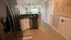 Una cocina moderna con refrigerador de acero inoxidable, armarios blancos y lavavajillas empotrado.