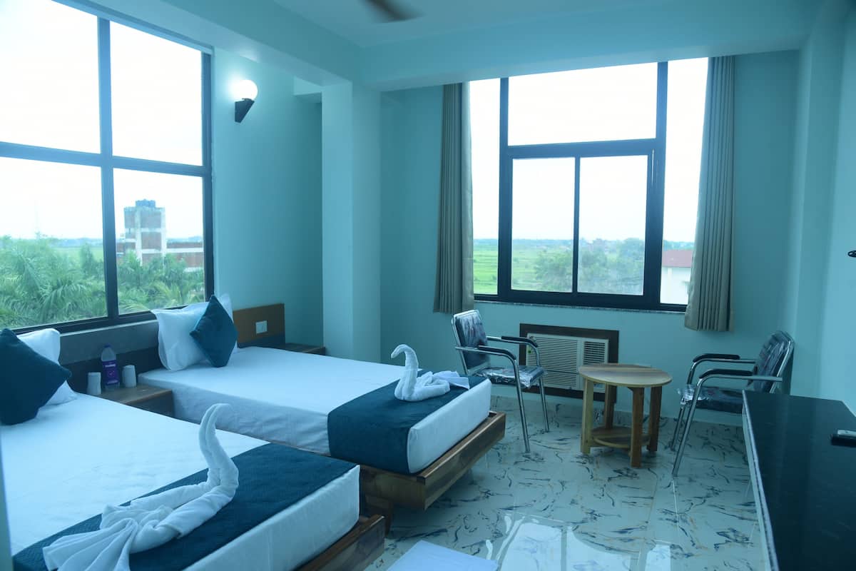 Une chambre d’hôtel avec deux lits, une petite table, des chaises et un bureau.