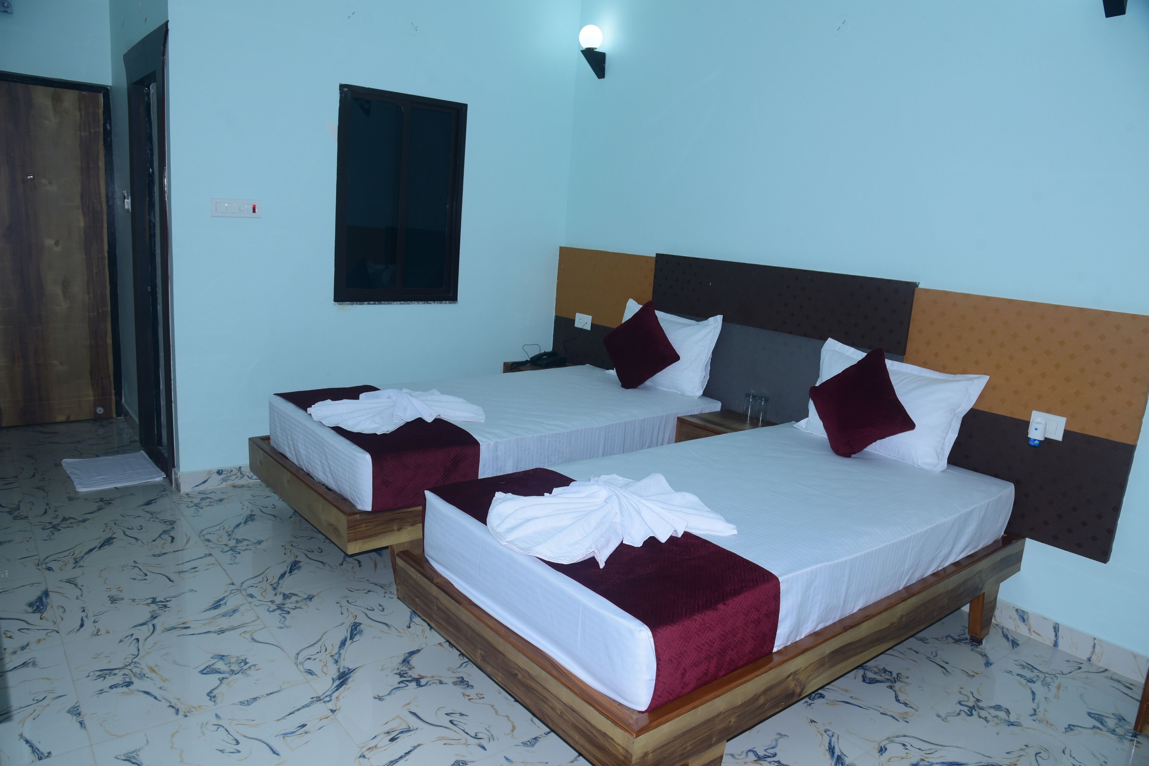Dos camas matrimoniales con estructuras y cabeceras de madera, ropa de cama blanca y almohadones rojos.