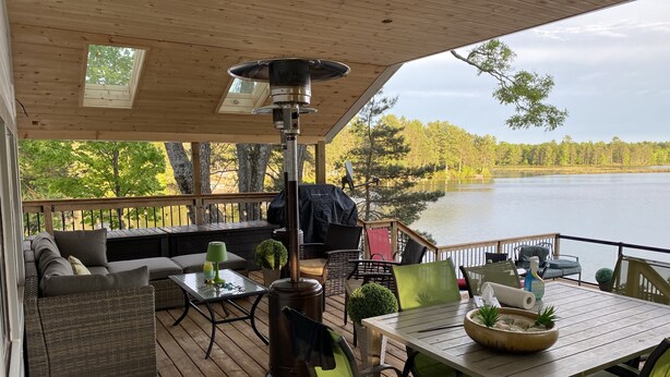 A covered deck with outdoor furniture, a table, and a wood-burning stove.