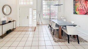 Een ruime eetruimte met een lange tafel en stoelen, een moderne kroonluchter en een groot raam met uitzicht op het omliggende landschap.