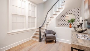 A staircase with a white railing and a gray chair in the landing area.