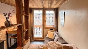 Ein kleines Zimmer mit einem Bett, einem Schreibtisch und einem Fenster mit Blick auf einen Balkon.