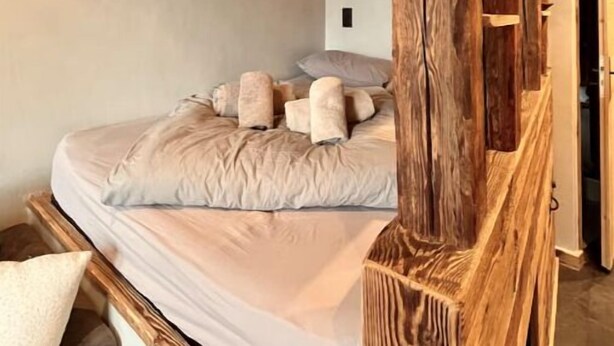 Ein Schlafzimmer mit Holzboden, einem Bett mit beige farbenen Bettwaren und einem hölzernen Kopfteil.