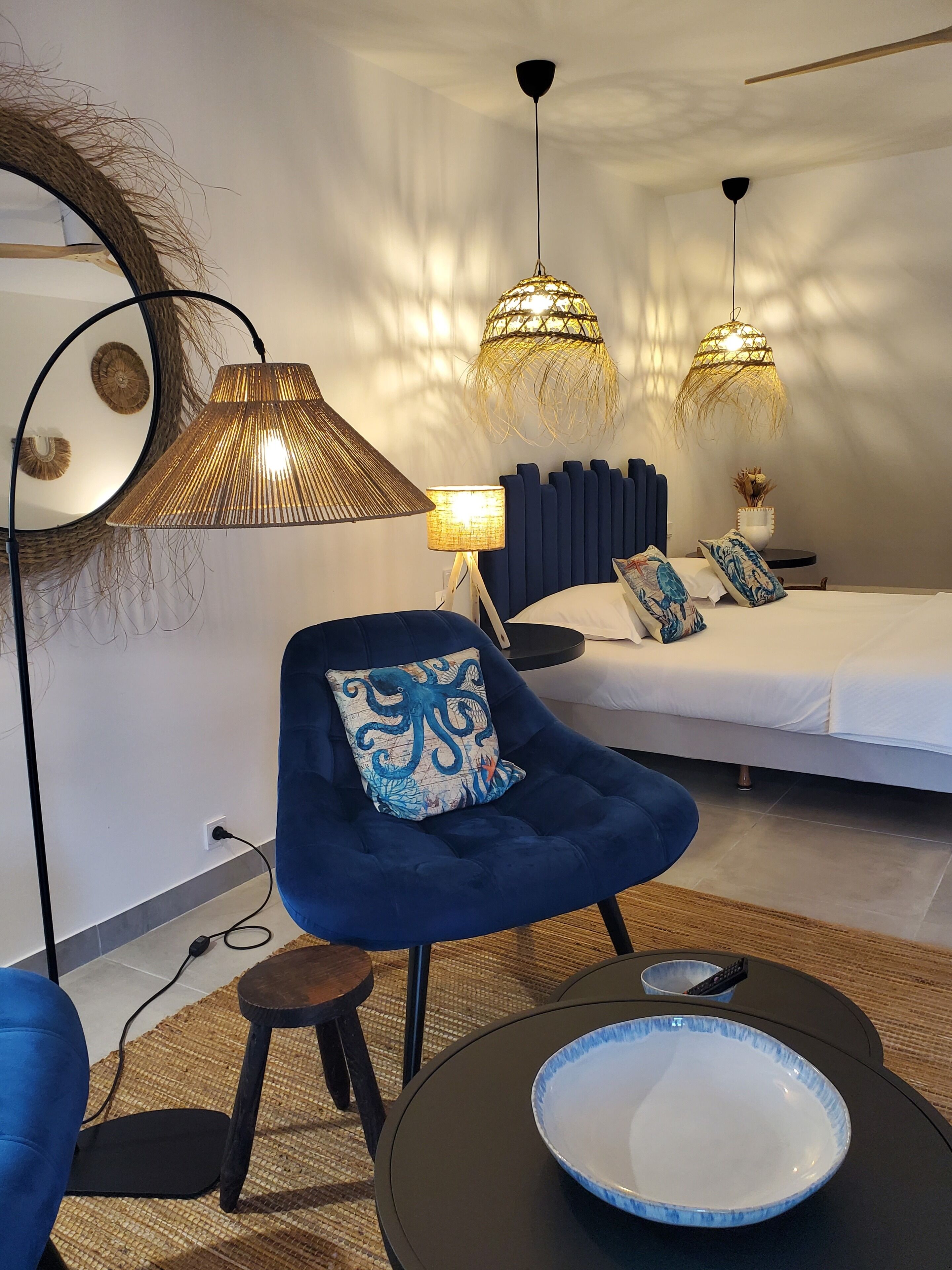 A modern bedroom with a bed, a blue chair, a bedside table, and two hanging lamps.
