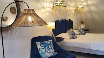 A modern bedroom with a bed, a blue chair, a bedside table, and two hanging lamps.