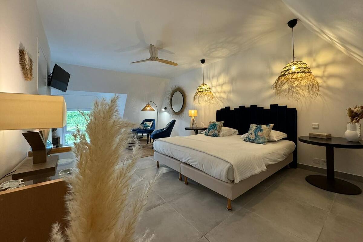 A modern bedroom with a large bed, two bedside lamps, a ceiling fan, and a TV mounted on the wall.